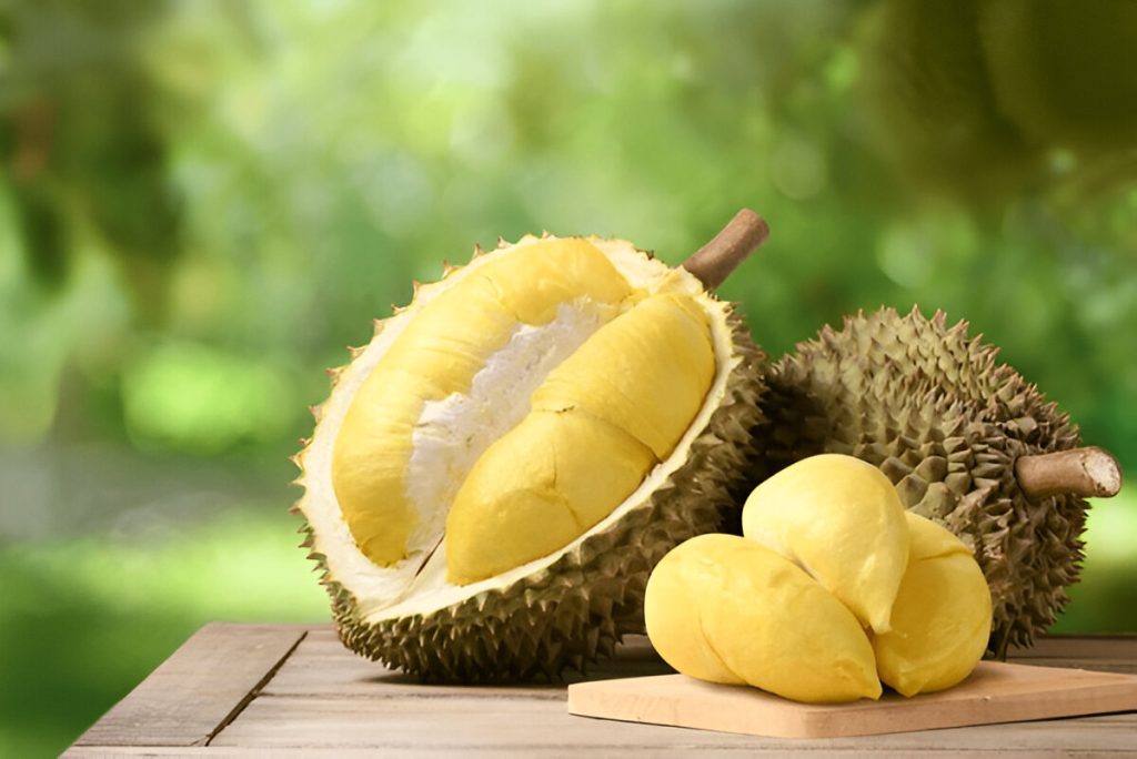 Buah durian di atas meja kayu dengan latar belakang perkebunan (shutterstock.com)