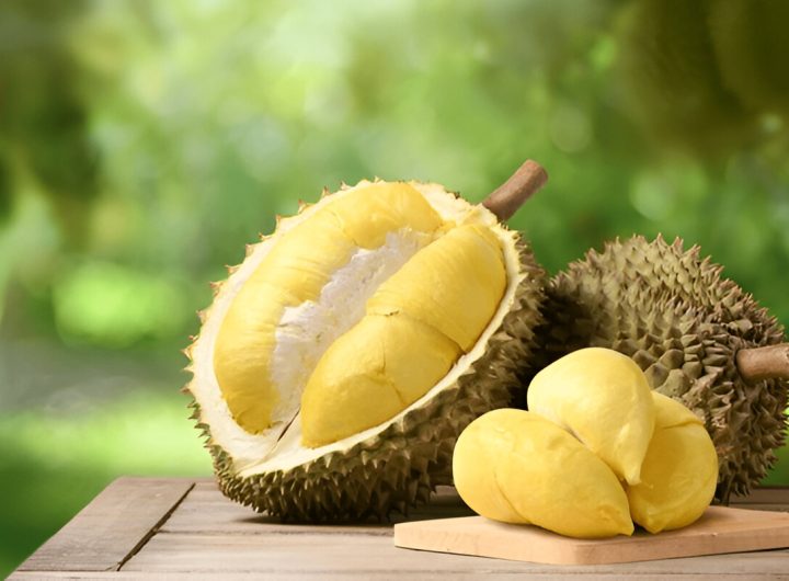 Buah durian di atas meja kayu dengan latar belakang perkebunan (shutterstock.com)