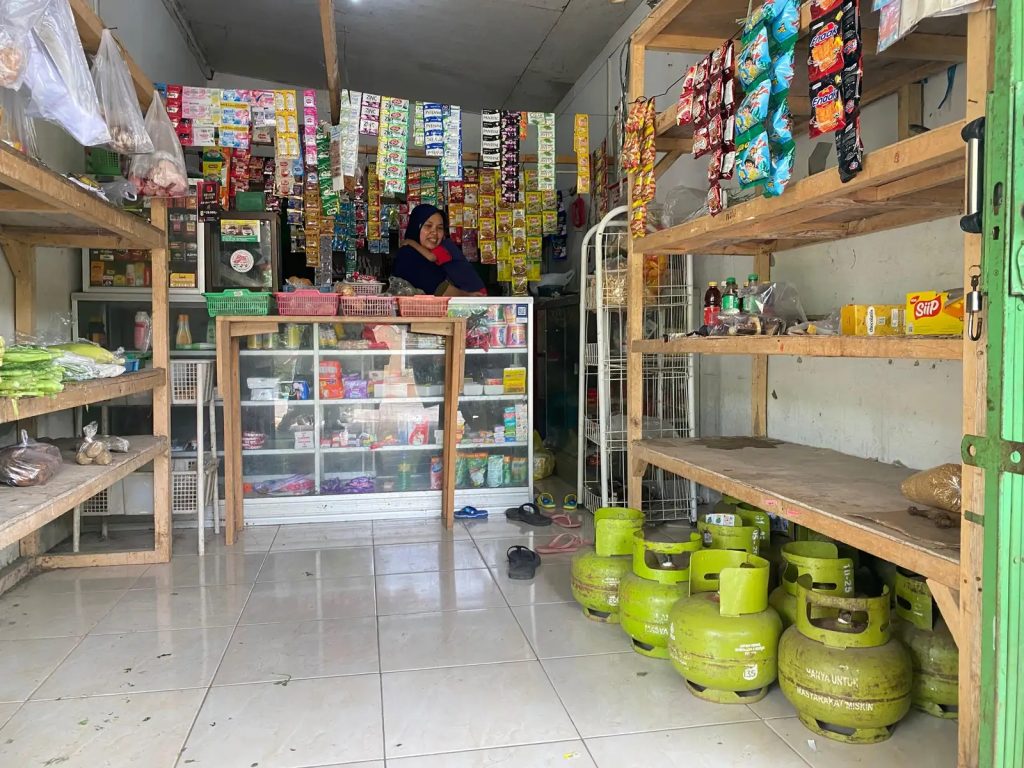 Foto Penjaga warung pengecer tabung gas elpiji tiga kilogram, Aisyah, saat menjaga warung dan ada tabung kosong di depannya (Tangkapan Layar)