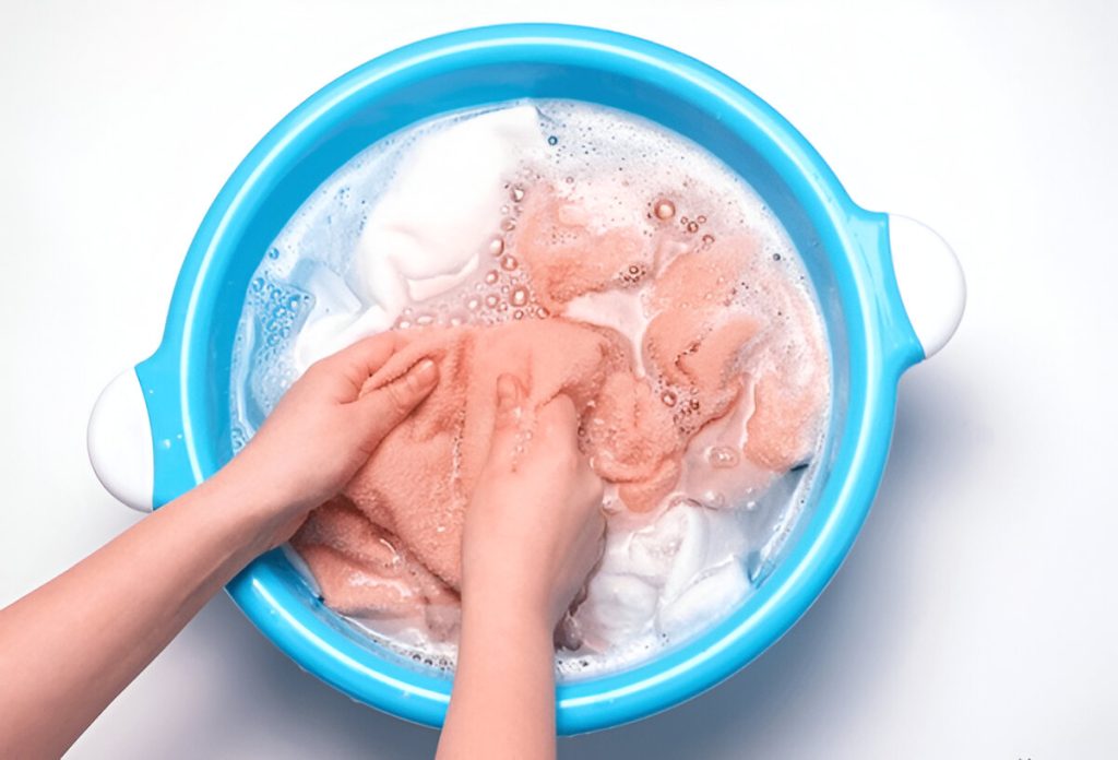 Tangan wanita mencuci handuk warna-warni di baskom (shutterstock.com)