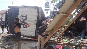 Diduga mengalami rem blong, truk kontainer bermuatan air mineral kemasan hilang kendali dan menabrak sebuah sepeda motor serta warung di tikungan menurun Jalan Raya Cirebon–Kuningan (Foto : Darfan)