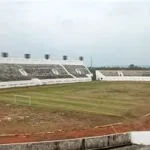 Rumput Stadion Watubelah Menguning, Kang Ohim Soroti Anggaran Perawatan **CIREBON** – Kondisi rumput Stadion Watubelah, Kecamatan Sumber, Kabupaten Cirebon, menjadi sorotan setelah hamparan lapangan utama berubah menjadi kuning kecokelatan dan mengering. Pemandangannya menyerupai sawah yang siap dipanen, berbeda dengan lapangan sepak bola yang seharusnya terlihat hijau dan terawat. Berdasarkan pantauan di lokasi pada Minggu, 18 Oktober 2026, rumput di sebagian besar permukaan lapangan utama terlihat mengering. Kondisi tersebut dilaporkan telah berlangsung lebih dari satu bulan dan memunculkan pertanyaan mengenai pemeliharaan fasilitas olahraga milik publik tersebut. Aktivis Cirebon, Abdulrohim atau yang akrab disapa Kang Ohim, mempertanyakan keseriusan pengelola dalam menjaga kondisi lapangan. Menurutnya, musim kemarau memang dapat memengaruhi pertumbuhan rumput, tetapi perawatan fasilitas seharusnya tetap berjalan. Kritik tersebut tidak hanya menyangkut penampilan lapangan, tetapi juga tanggung jawab pengelola, penggunaan anggaran pemeliharaan, serta pungutan yang dikenakan kepada masyarakat yang berkunjung. ## Kang Ohim Pertanyakan Pemeliharaan Stadion Watubelah Kang Ohim menilai kondisi rumput yang mengering perlu menjadi perhatian serius. Ia mempertanyakan pola pemeliharaan yang dilakukan hingga lapangan utama Stadion Watubelah mengalami perubahan warna secara luas. Menurutnya, fasilitas olahraga yang memiliki pengelola seharusnya mendapatkan perawatan rutin, termasuk ketika menghadapi cuaca kering. Pemeliharaan tersebut diperlukan agar kondisi rumput tidak semakin memburuk dan lapangan tetap dapat dimanfaatkan sesuai fungsinya. Ia juga mempertanyakan klaim mengenai perawatan rumput melalui penyiraman dan pemupukan. Kondisi lapangan yang terlihat saat ini, menurutnya, menimbulkan keraguan terhadap efektivitas pemeliharaan tersebut. Kang Ohim menilai persoalan ini tidak semestinya hanya dijelaskan melalui faktor cuaca. Pengelola perlu memberikan keterangan mengenai langkah perawatan yang telah dilakukan dan upaya yang disiapkan untuk menangani kondisi rumput. ## Anggaran Perawatan Ikut Menjadi Sorotan Selain kondisi lapangan, penggunaan anggaran pemeliharaan turut dipertanyakan. Kang Ohim menyoroti peran Dinas Pemuda dan Olahraga (Dispora) Kabupaten Cirebon dalam kaitannya dengan anggaran perawatan Stadion Watubelah. Ia mempertanyakan sejauh mana anggaran tersebut digunakan dan bagaimana hasil pemeliharaannya dapat dilihat secara nyata. Sorotan ini penting karena perawatan lapangan sepak bola membutuhkan penanganan yang berkelanjutan. Penyiraman, pemupukan, pemotongan rumput, serta pemeriksaan kondisi tanah merupakan beberapa aspek yang perlu diperhatikan agar kualitas lapangan tetap terjaga. Namun, kondisi rumput yang mengering belum cukup untuk membuktikan adanya penyimpangan dalam penggunaan anggaran. Diperlukan penjelasan mengenai alokasi dana, kegiatan pemeliharaan yang telah dilaksanakan, serta evaluasi hasil perawatan untuk mengetahui persoalan secara menyeluruh. Karena itu, transparansi dari pihak terkait dibutuhkan agar masyarakat memperoleh informasi yang jelas mengenai pengelolaan fasilitas olahraga tersebut. ## Pungutan Pengunjung Juga Dipertanyakan Persoalan lain yang disoroti Kang Ohim adalah pungutan terhadap pengunjung Stadion Watubelah. Ia menyebut masyarakat harus membayar karcis parkir dan kembali dikenai tarif ketika memasuki area stadion. Menurutnya, mekanisme pungutan dan penggunaan pendapatan dari aktivitas kawasan stadion perlu dijelaskan secara terbuka. Ia mempertanyakan apakah penerimaan tersebut turut mendukung biaya operasional dan pemeliharaan fasilitas. Kondisi ini memunculkan pertanyaan mengenai hubungan antara pengelolaan kawasan stadion dan kualitas fasilitas yang dapat dinikmati masyarakat. Kejelasan mengenai dasar penarikan tarif, pihak yang bertanggung jawab, serta peruntukan penerimaan menjadi penting agar pengelolaan fasilitas publik dapat dipertanggungjawabkan. ## Warga Kecewa Melihat Kondisi Rumput Kondisi rumput yang mengering juga menimbulkan kekecewaan bagi warga yang datang untuk berolahraga. Naim, salah seorang warga yang berkunjung ke Stadion Watubelah untuk berjoging, mengaku terkejut melihat perubahan kondisi lapangan. Ia menyebut rumput stadion beberapa bulan sebelumnya masih terlihat hijau. Menurutnya, kondisi tersebut sangat disayangkan karena Stadion Watubelah memiliki potensi menjadi ruang olahraga yang nyaman bagi masyarakat. Keluhan warga ini memperlihatkan bahwa pemeliharaan stadion tidak hanya berkaitan dengan kebutuhan atlet atau penyelenggaraan pertandingan. Kondisi fasilitas juga memengaruhi pengalaman masyarakat yang memanfaatkan kawasan tersebut untuk beraktivitas fisik. ## Perlu Evaluasi dan Penjelasan Pengelola Musim kemarau dapat meningkatkan risiko kekeringan pada rumput lapangan terbuka. Berkurangnya ketersediaan air dan meningkatnya penguapan dapat membuat rumput berubah warna, terutama jika kebutuhan air tidak terpenuhi. Meski demikian, penyebab pasti kondisi rumput Stadion Watubelah tetap perlu dipastikan melalui pemeriksaan lapangan. Evaluasi diperlukan untuk mengetahui apakah kekeringan dipengaruhi oleh cuaca, kondisi tanah, sistem penyiraman, atau faktor pemeliharaan lainnya. Hingga berita ini disusun, sumber pemberitaan yang tersedia belum memuat penjelasan resmi pengelola mengenai penyebab rumput mengering, kegiatan perawatan yang telah dilakukan, maupun rencana pemulihan lapangan. Kondisi ini menjadi pengingat bahwa pengelolaan fasilitas olahraga publik perlu disertai pemeliharaan berkelanjutan dan transparansi. Masyarakat tentu berharap Stadion Watubelah tetap menjadi tempat olahraga yang layak, nyaman, dan terawat. Penjelasan dari pihak pengelola dan instansi terkait kini diperlukan untuk menjawab pertanyaan mengenai kondisi rumput, penggunaan anggaran perawatan, serta langkah konkret yang akan dilakukan agar lapangan kembali berfungsi secara optimal