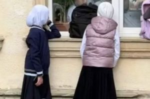 # Azerbaijan, Negara Mayoritas Muslim, Siswi Berhijab Dilaporkan Dilarang Masuk Sekolah **AZERBAIJAN** – Kebijakan seragam sekolah di Azerbaijan memicu kontroversi setelah sejumlah siswi berhijab dilaporkan ditolak masuk kelas. Kebijakan tersebut menjadi sorotan karena Azerbaijan merupakan negara dengan sekitar 96 persen penduduk beragama Islam, tetapi menerapkan prinsip sekularisme dalam sistem pemerintahannya. Persoalan ini mencuat setelah pemerintah Azerbaijan mengesahkan perubahan aturan seragam sekolah pada 21 September 2026. Aturan baru tersebut melarang penggunaan pakaian yang dianggap tidak sesuai dengan ketentuan seragam atau bertentangan dengan prinsip sekuler dalam pendidikan. Meskipun ketentuan itu tidak secara eksplisit menyebut hijab sebagai pakaian terlarang, penerapannya di sejumlah sekolah dilaporkan membuat siswi yang mengenakan penutup kepala tidak diperbolehkan mengikuti kegiatan belajar mengajar. Persoalan ini kemudian memicu protes dari siswa, orang tua, dan sejumlah guru. Perdebatan berkembang menjadi pembahasan mengenai batas antara aturan pendidikan sekuler dan kebebasan beragama di negara tersebut. ## Siswi Berhijab Ditolak Masuk Kelas Sejumlah laporan media internasional menyebutkan bahwa penegakan aturan seragam baru mulai berdampak pada siswa dan guru pada Oktober 2026. Di Sekolah Nomor 6 di Kota Sumqayit, misalnya, beredar video yang memperlihatkan siswi berhijab memeluk guru mereka sambil menangis setelah menghadapi pembatasan masuk sekolah. Rekaman tersebut kemudian menyebar di media sosial dan menarik perhatian publik. Laporan lain menyebutkan bahwa sejumlah siswi di Baku dan wilayah lain juga mengalami penolakan serupa. Beberapa orang tua mengaku anak mereka tidak diperbolehkan mengikuti pelajaran apabila tetap mengenakan hijab. Guru perempuan turut terdampak oleh penerapan aturan tersebut. Al Jazeera melaporkan seorang guru bahasa Inggris bernama Gulshan Aliyeva tidak diperbolehkan masuk ke sekolah tempatnya bekerja karena mengenakan penutup kepala. Putrinya juga dilaporkan menghadapi pembatasan serupa. Situasi tersebut memunculkan kekhawatiran mengenai keberlanjutan pendidikan siswa dan pekerjaan tenaga pengajar yang memilih tetap mengenakan hijab. ## Mengapa Hijab Dipersoalkan di Azerbaijan? Pemerintah Azerbaijan mendasarkan kebijakan seragam sekolah pada prinsip sekularisme. Dalam sistem tersebut, negara dan lembaga publik memiliki aturan yang memisahkan urusan pemerintahan dari agama. Melalui perubahan ketentuan seragam, pemerintah berupaya menerapkan standar berpakaian yang seragam di sekolah negeri. Pihak pendukung aturan berpendapat bahwa ketentuan tersebut bertujuan menjaga keseragaman dan mencerminkan karakter pendidikan sekuler. Namun, penerapannya menimbulkan persoalan karena aturan mengenai pakaian yang bertentangan dengan prinsip sekularisme dinilai dapat digunakan untuk membatasi penggunaan hijab. Azerbaijan sendiri merupakan negara sekuler berdasarkan konstitusinya. Pasal 7 menetapkan karakter negara yang sekuler, sedangkan Pasal 18 mengatur hubungan agama dan negara serta sifat sekuler pendidikan. Di sisi lain, Pasal 48 menjamin kebebasan hati nurani. Ketentuan tersebut membuat perdebatan tidak hanya berkaitan dengan pakaian sekolah, tetapi juga bagaimana negara menyeimbangkan prinsip pendidikan sekuler dengan hak warga untuk menjalankan keyakinan mereka. ## Protes Muncul, Puluhan Orang Dilaporkan Ditahan Penolakan terhadap pembatasan hijab memicu aksi protes di sejumlah wilayah Azerbaijan. Selain demonstrasi, laporan media menyebutkan siswa di setidaknya dua sekolah melakukan boikot kelas sebagai bentuk solidaritas. Sebagian siswa laki-laki juga dilaporkan memilih tidak mengikuti pelajaran untuk mendukung teman perempuan mereka yang terdampak aturan tersebut. Menurut Al Jazeera, Kementerian Dalam Negeri Azerbaijan menyatakan bahwa 37 orang ditahan pada 12 Oktober 2026 terkait insiden yang disebut mengganggu ketertiban umum. Pihak berwenang menuduh para demonstran terlibat dalam konfrontasi dengan petugas pendidikan, merusak fasilitas, atau menghambat kegiatan sekolah dan lalu lintas. Penahanan tersebut menjadi bagian lain dari kontroversi yang berkembang di tengah penerapan aturan seragam. Sementara itu, kelompok yang menentang pembatasan menilai hak atas pendidikan dan kebebasan beragama perlu tetap dilindungi. ## Pemerintah dan Penentang Memiliki Pandangan Berbeda Pemerintah dan sejumlah pendukung kebijakan menegaskan bahwa aturan tersebut ditujukan untuk mengatur seragam sekolah, bukan melarang agama tertentu. Anggota parlemen Zahid Oruj, misalnya, menyatakan bahwa ketentuan itu tidak dimaksudkan sebagai diskriminasi agama. Sebaliknya, pihak yang menentang kebijakan menilai pembatasan terhadap siswi berhijab dapat menghambat hak mereka untuk memperoleh pendidikan. Mereka juga mempertanyakan mengapa pilihan berpakaian yang berkaitan dengan keyakinan harus menjadi penghalang untuk mengikuti pelajaran. Perdebatan ini turut mendapat perhatian dari Turki. Seorang penasihat Presiden Turki Recep Tayyip Erdogan mengkritik pembatasan tersebut. Tanggapan itu kemudian memicu balasan dari partai berkuasa Azerbaijan yang menilai komentar tersebut berisiko memengaruhi hubungan kedua negara. Hingga pertengahan Oktober 2026, persoalan ini masih menjadi perdebatan publik. Perkembangan berikutnya akan bergantung pada penerapan aturan di sekolah, respons pemerintah, serta kemungkinan upaya hukum dari pihak yang merasa dirugikan. Kasus Azerbaijan memperlihatkan bahwa status sebagai negara mayoritas Muslim tidak selalu berarti seluruh kebijakan publik didasarkan pada aturan agama. Pada saat yang sama, penerapan prinsip sekularisme juga memunculkan pertanyaan mengenai cara melindungi kebebasan beragama tanpa mengabaikan ketentuan pendidikan yang berlaku.
